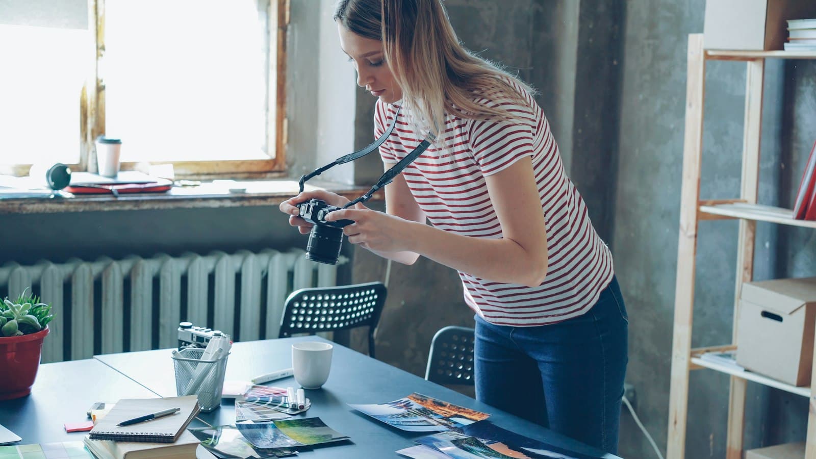A small-business owner photographing printed products laid out on a worktable