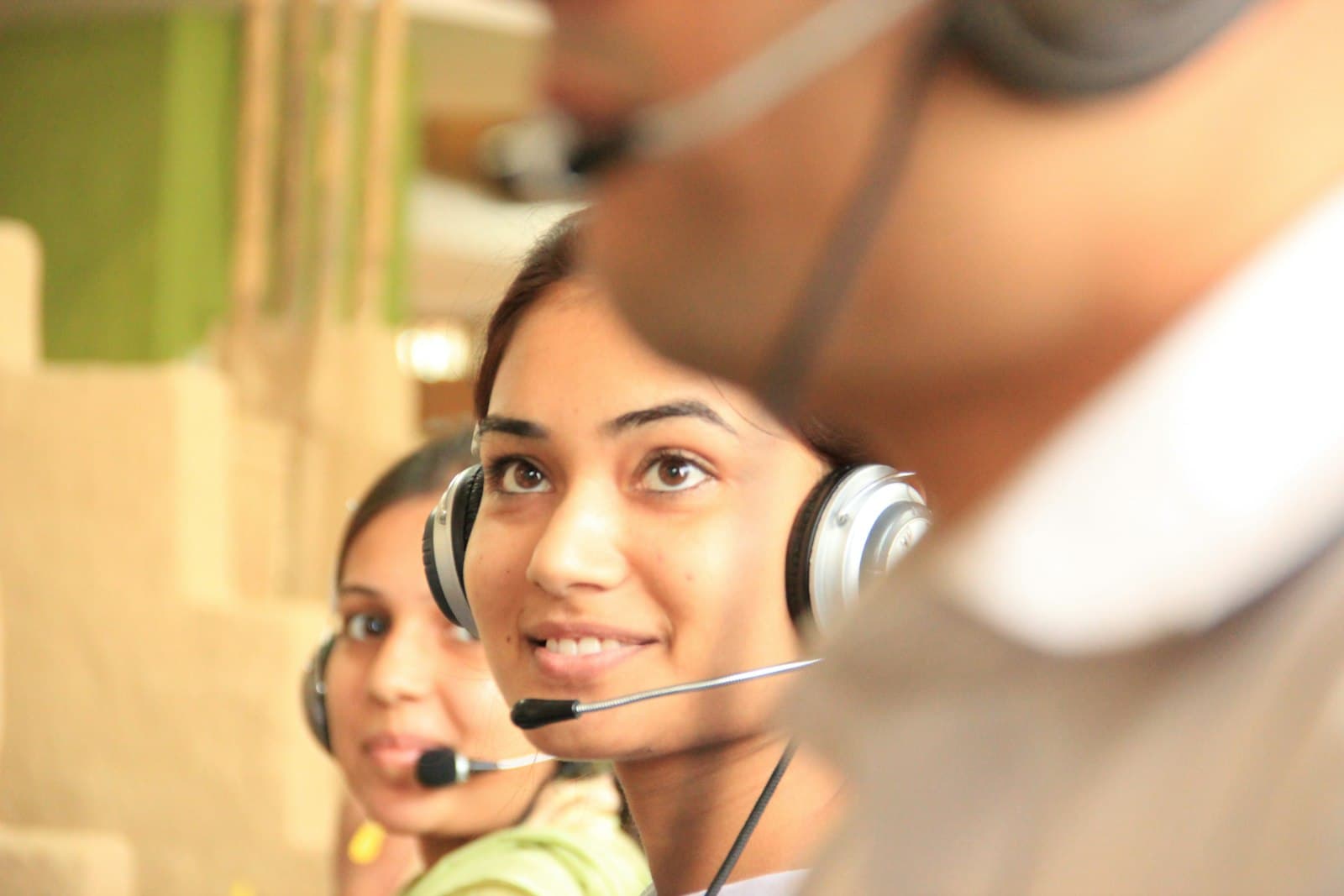 Two support agents in headsets working through calls at their desks in a bright office